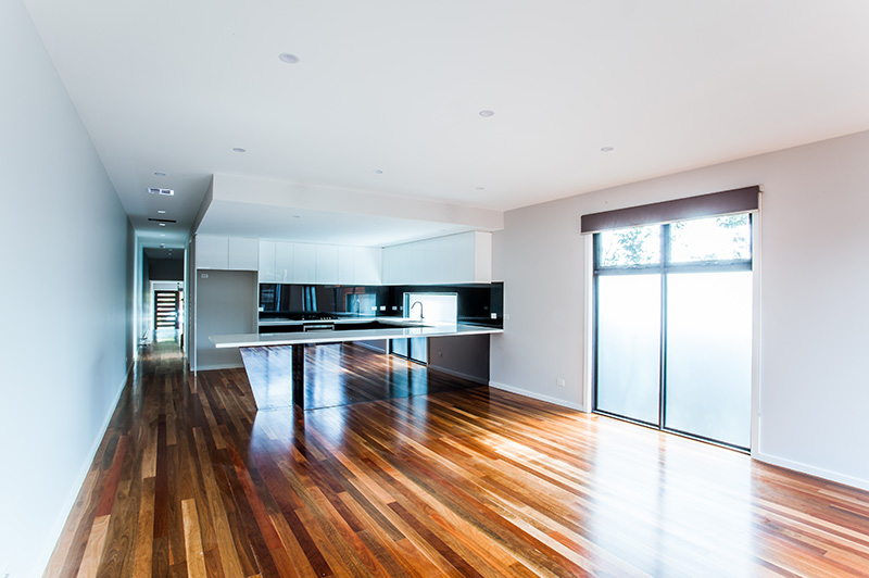 Kitchen with stone bench tops and black mirrored cabinets in the Mordialloc custom home
